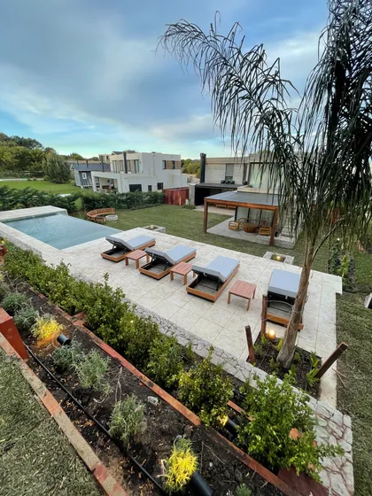 piscina moderna con deck, mobiliario y vegetación exuberante — proyecto COSTA ESMERALDA, por Baires Green, en Pinamar