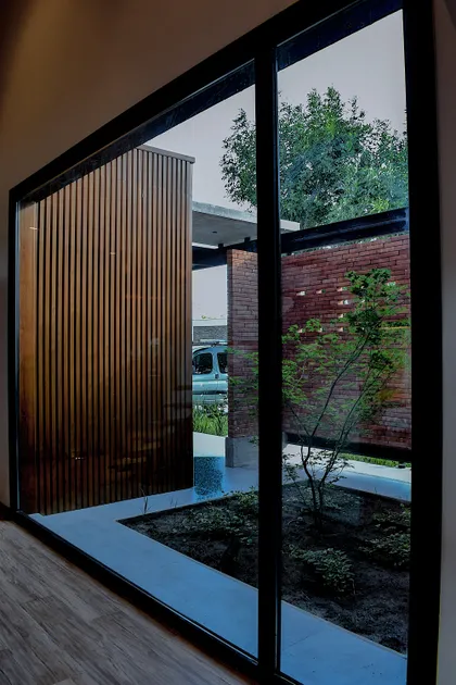 fachada moderna con lamas de madera y patio integrado — proyecto CASA HC, por Daniel Daniele - Oficina de Arquitectura, en Canning