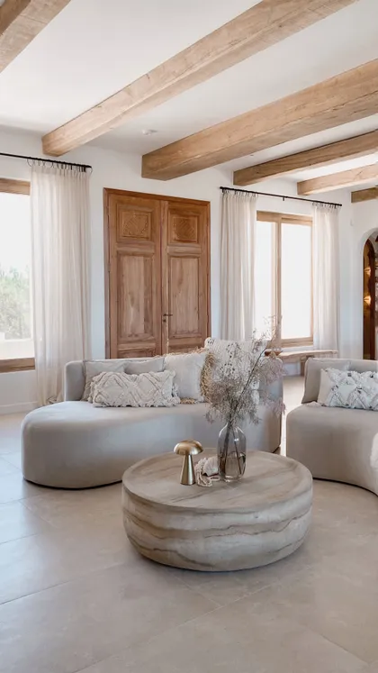 Sala de estar mediterránea con vigas de madera expuestas y sofá curvo — proyecto El Refugio, por Grupo Pauta Arquitectura, en Pinamar