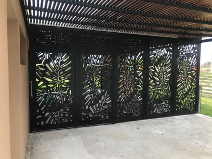 Portón negro calado de hojas con pérgola de madera — proyecto Chapa calada decorativa, tríptico árbol de la vida oara portones corredizos y ce, por Pintastic, en Belén de Escobar