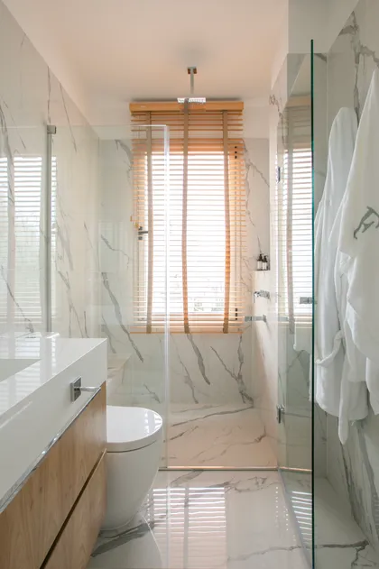Baño moderno escandinavo con mármol, madera y ducha de vidrio — proyecto Obra Newman M, por Arq. Lourdes Yarade Saravia, en Benavidez