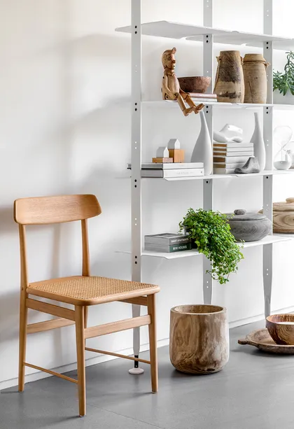 Living escandinavo con estanterías blancas y silla de madera — proyecto Projeto BJ, por Simara Deola Mello