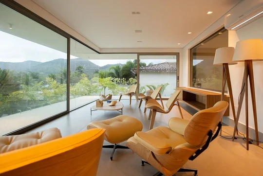 Terraza moderna con sillones de madera, grandes ventanales y vistas montañosas — proyecto Casa Nort, por Toledo Arquitetura E Design