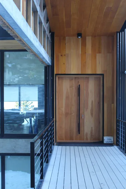 Fachada moderna con puerta doble de madera y decks — proyecto Casa Península San Pedro, por Servente Larrazabal Arq, en Bariloche