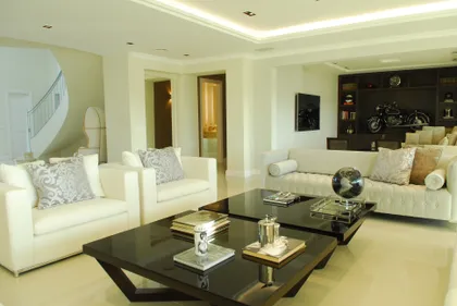 Living moderno blanco con sofá curvo y moto de exhibición — proyecto Chateau al Río, por Apaarquitectura, en Tigre