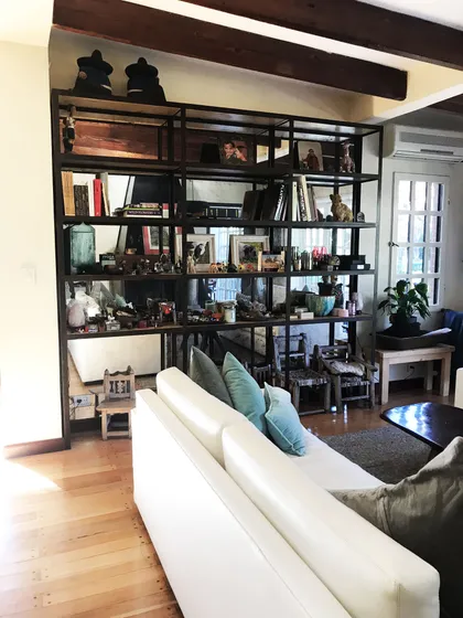 Amplio living con estantería negra, sofá blanco y vigas de madera — proyecto Monroe - La Horqueta, por Mgc.arq, en La Horqueta