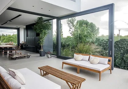 Living moderno con grandes ventanales y mobiliario de exterior — proyecto Rampa, por Remy Arquitectos