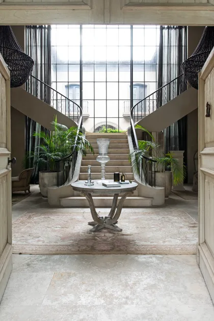 Hall doble altura con escalera central, plantas y gran ventanal — proyecto Casa Toscana , por Estudio Du 