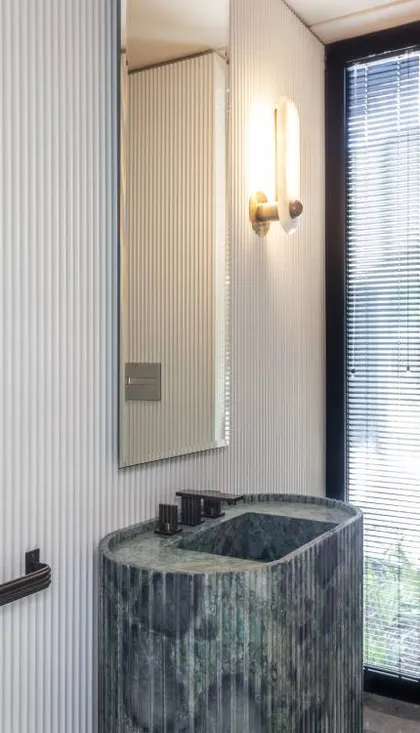 Baño moderno con lavabo de piedra verde acanalado y pared de listones — proyecto Casa Órbita, por Estudio PK, en Nordelta