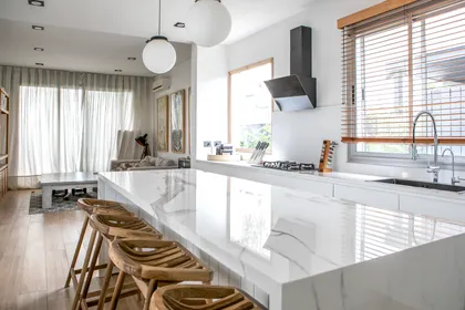 Cocina moderna abierta con isla de mármol, pisos de madera y luces colgantes — proyecto Obra El Encuentro, por Arq. Lourdes Yarade Saravia, en Benavidez