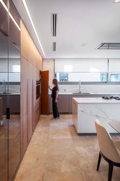 Cocina moderna con isla de mármol, madera natural y luz indirecta — proyecto Water House, por Remy Arquitectos, en Rincón de Milberg