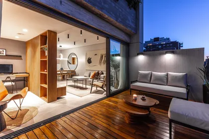 terraza de apartamento moderna con deck de madera y vista urbana — proyecto Depto Valle, por Ayelen Mayer Arquitectura, en Buenos Aires