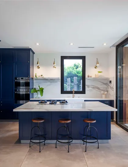 Cocina moderna azul con isla de mármol y taburetes minimalistas — proyecto Los Castores, Nordelta, por Build a Home Arquitectura, en Nordelta