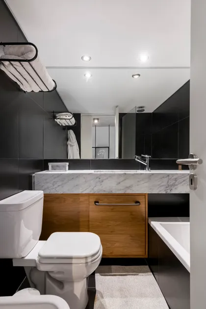 Baño moderno con azulejos negros, mármol y mueble de madera — proyecto Nicaragua, por SRMD Arquitectura, en Palermo
