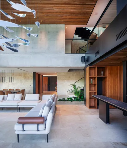 Living moderno de doble altura con iluminación escultural y detalles en madera — proyecto Water House, por Remy Arquitectos, en Rincón de Milberg