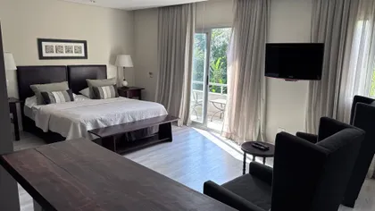 Habitación de hotel moderna con paneles de tela beige y cama grande — proyecto Villa Isidro Hotel Boutique & Spa, por Hermann Arquitectos, en San Isidro