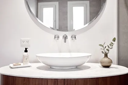 Baño moderno con espejo redondo y bacha sobre mesada de piedra — proyecto Figueroa Alcorta, por Equipe, en Buenos Aires