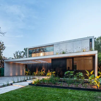 Fachada moderna de hormigón con ventanales y vegetación integrada — proyecto CASA AH, por GMARQ, en Garin