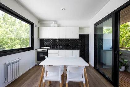 Cocina y comedor modernos integrados con mucha luz y vista al verde — proyecto Terrazas de Saavedra, por DREI Arquitectura y Desarrollos, en La Plata