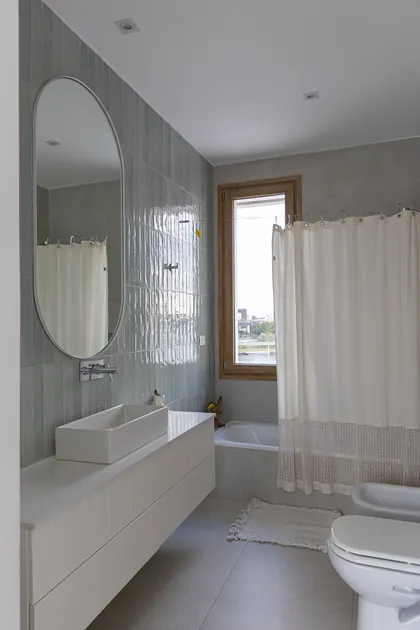 Baño moderno con espejo arqueado, vanitory flotante y ducha de tela — proyecto Casa Al Agua - Grupo PAUTA, por Gaby Alfonso, en Belén de Escobar