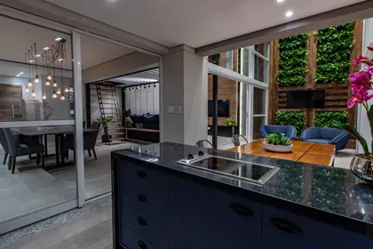 Cocina moderna con isla de marmol negro y jardin vertical integrado — proyecto Duo Morumbi, por Pricila Dalzochio