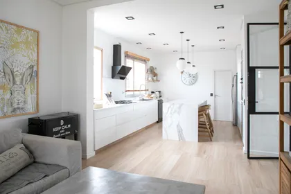 Cocina moderna y luminosa con isla, suelo de madera y arte — proyecto Obra El Encuentro, por Arq. Lourdes Yarade Saravia, en Benavidez
