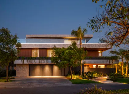 fachada moderna de casa con maderas y luces cálidas — proyecto Water House, por Remy Arquitectos, en Rincón de Milberg