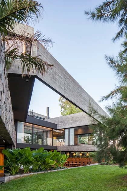 Casa moderna de hormigón con grandes ventanales y vegetación exuberante — proyecto Casa Nomade, por Remy Arquitectos, en B1648 Tigre