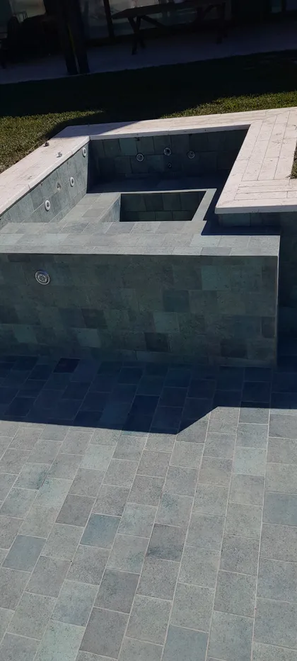 pileta moderna con bordes hormigon y deck de piedra gris — proyecto piscina con hidromasaje, por Piscinas omar, en San Isidro