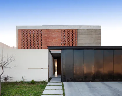 Fachada moderna con ladrillos perforados y puerta de garaje espejada — proyecto CASA BSB, por BUSCETTI & DI BERNARDO arquitectas, en Gonnet