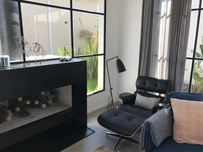 Living moderno con chimenea negra y grandes ventanales — proyecto Casa Las Liebres, por Mazzinghi Sanchez, en Garin