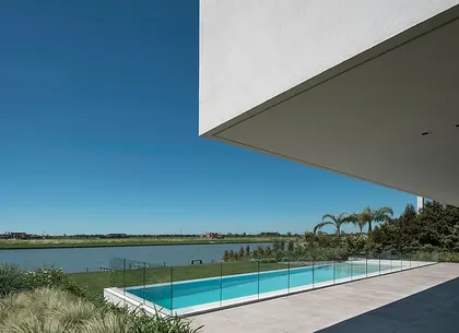 Piscina moderna con deck de hormigón y vista al agua — proyecto Casa Lombardi, por Estudio Ramos
