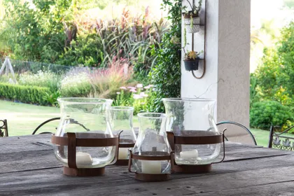 Patio rústico con faroles de cristal y madera — proyecto Proyecto Santa Barbara, por Mechi Bruni, en Benavidez