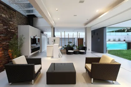 Living moderno interior-exterior con piedra y rattan — proyecto Devoto, por Remy Arquitectos, en CABA
