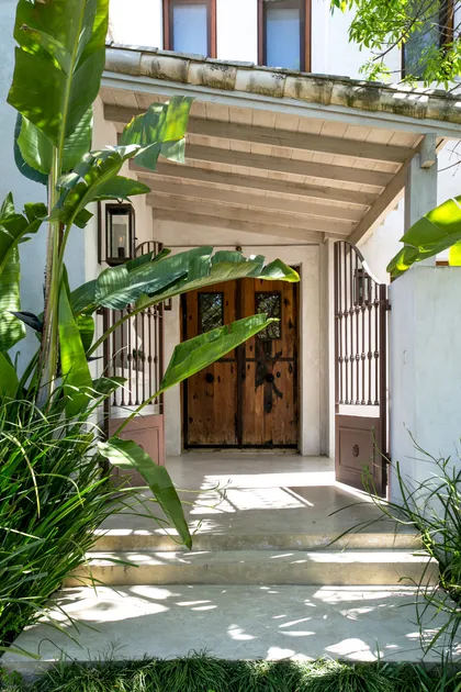 Entrada rústica con puertas de madera y vegetación exuberante — proyecto Club Newman 4, por Escalante Vela Arquitectos, en Benavidez