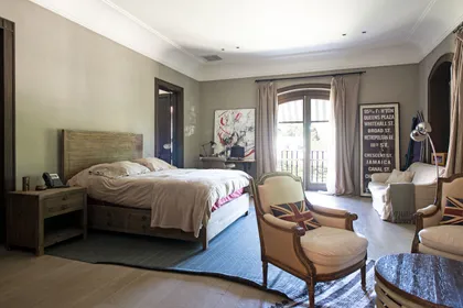 Dormitorio principal luminoso con cama de madera y sillones tapizados — proyecto Casa Toscana , por Estudio Du