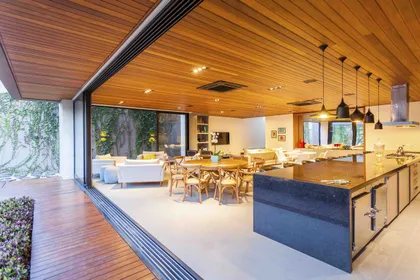 Cocina moderna con isla, techo de madera y vista al jardín — proyecto Casa MaCa, por Studio Jordano Valota