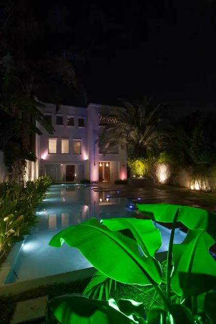 Piscina moderna de noche con vegetación exuberante y iluminación cálida — proyecto Detalles, por Geo Estudio, en Buenos Aires