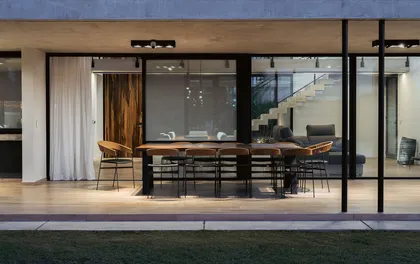 Comedor moderno con grandes ventanales, muebles de madera y piso de hormigon — proyecto Horizon House, por Estudio UFV72, en B2814 Los Cardales