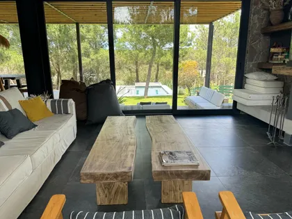 Living moderno con vista al bosque y mesas de madera natural — proyecto Casa CE, por Estudio FORSCH, en Pinamar