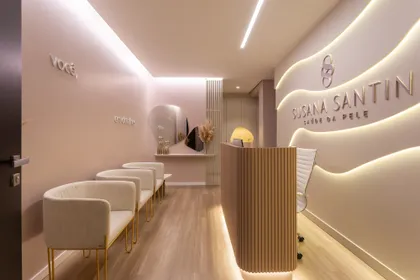 Interior comercial moderno beige con paredes curvas e iluminación indirecta, recepción de madera y sillas de espera — proyecto #ConsultórioSusanaSantin, por Oficina de Morar