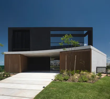 Fachada moderna de dos pisos con volúmenes geométricos y detalles en madera — proyecto CASA MUELLES, por GMARQ, en Escobar