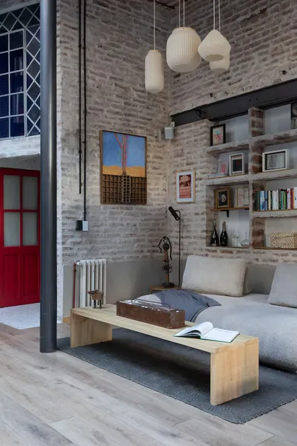 Sala de estar industrial con ladrillos expuestos y lámparas colgantes — proyecto Casa Arcos, por Silvia Soqueff, en Núñez