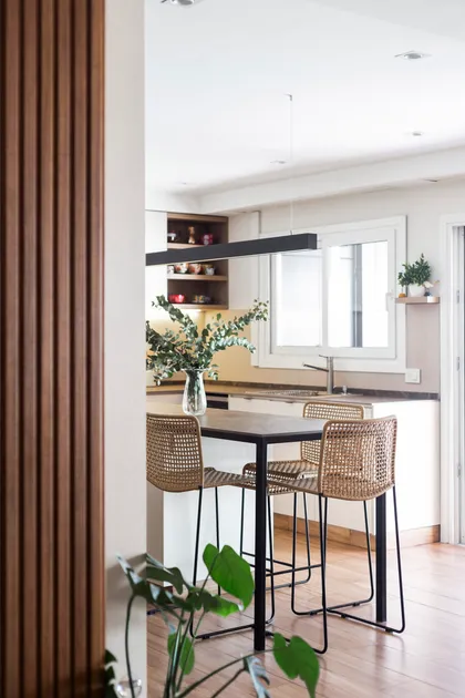 Cocina moderna con pared de lamas de madera y comedor integrado — proyecto Casa en Martinez, por JT ARQUITECTURA, en Martínez