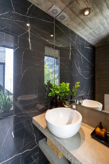 Baño moderno con paredes de mármol negro y detalles de cemento — proyecto Casa Tres Patios, por Besonías Almeida arquitectos, en Pilar