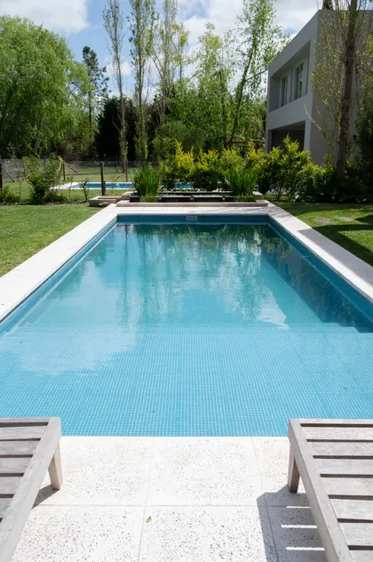 Piscina moderna rodeada de vegetación y zona de descanso — proyecto Campo grande III, por Juarez-Fevre Estudio de Arquitectura , en Buenos Aires