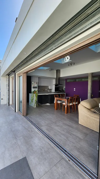 Cocina moderna abierta con comedor y sala, patio con puertas corredizas y vegetación — proyecto Casa Berner, por Zima Arquitectura, en La Plata