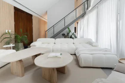 Living moderno con sofá curvo blanco y escalera flotante — proyecto PROYECTO NAUDIR, por July Acosta Home, en Belén de Escobar