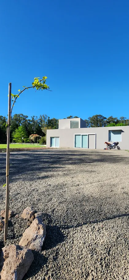 Casa moderna con entrada de grava y cielo azul — proyecto Casa VAL, por Estudio Rifahi, en Capilla del Señor