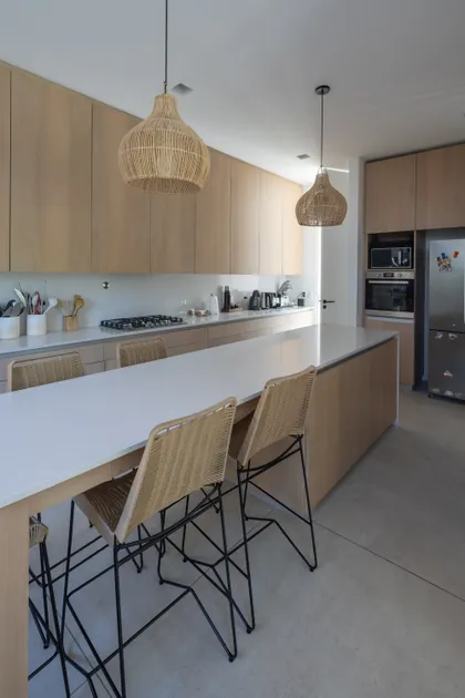 Cocina moderna con isla de madera, iluminación cálida y muebles de estilo escandinavo — proyecto CASA BaCa, por Alfredo Orfila arquitectura, en Benavidez